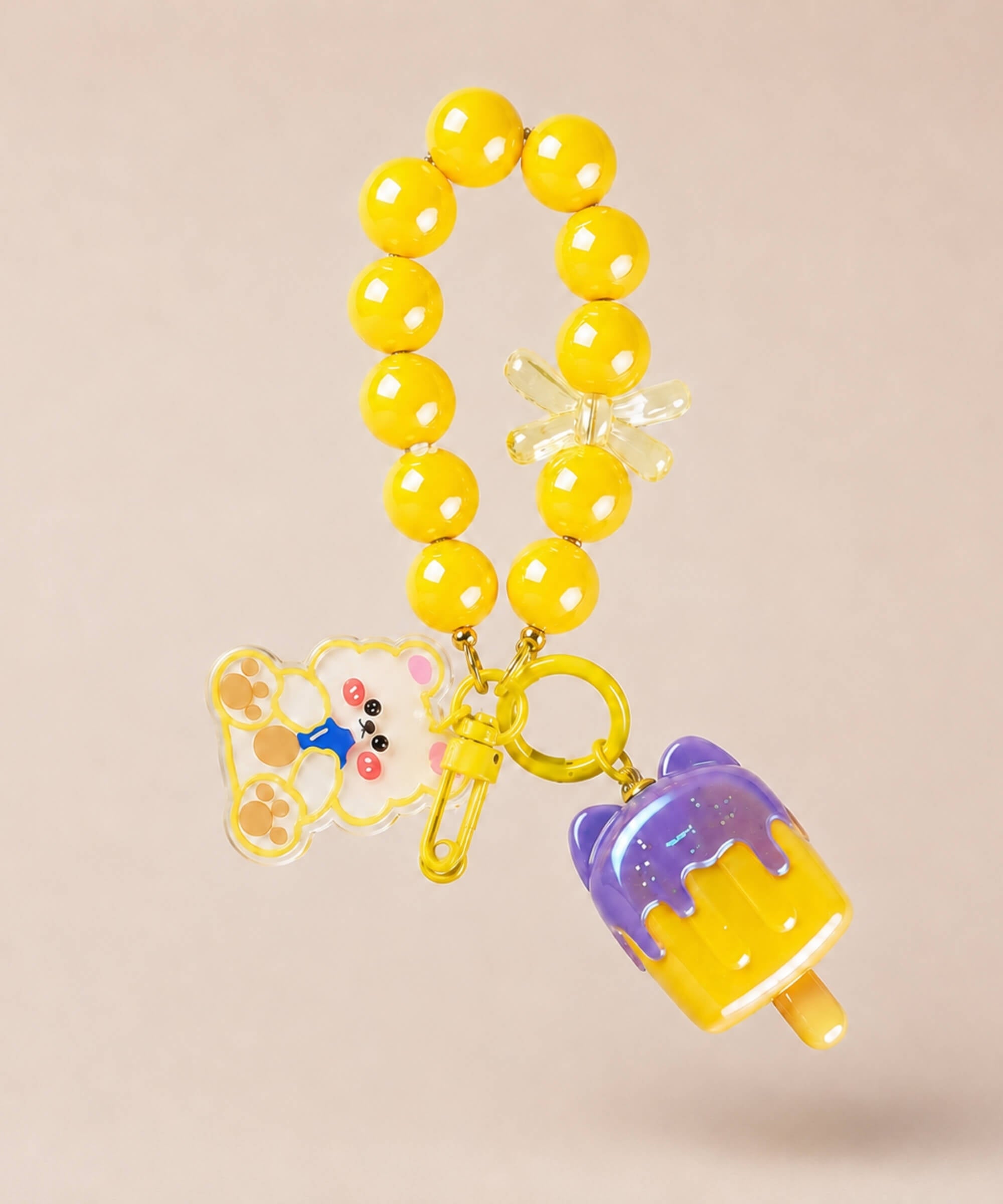 Yellow ice cream beaded keychain with yellow beads and bear charm on a neutral background