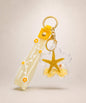 Yellow starfish liquid keychain with yellow glitter, shell detail, floral strap and gold hardware