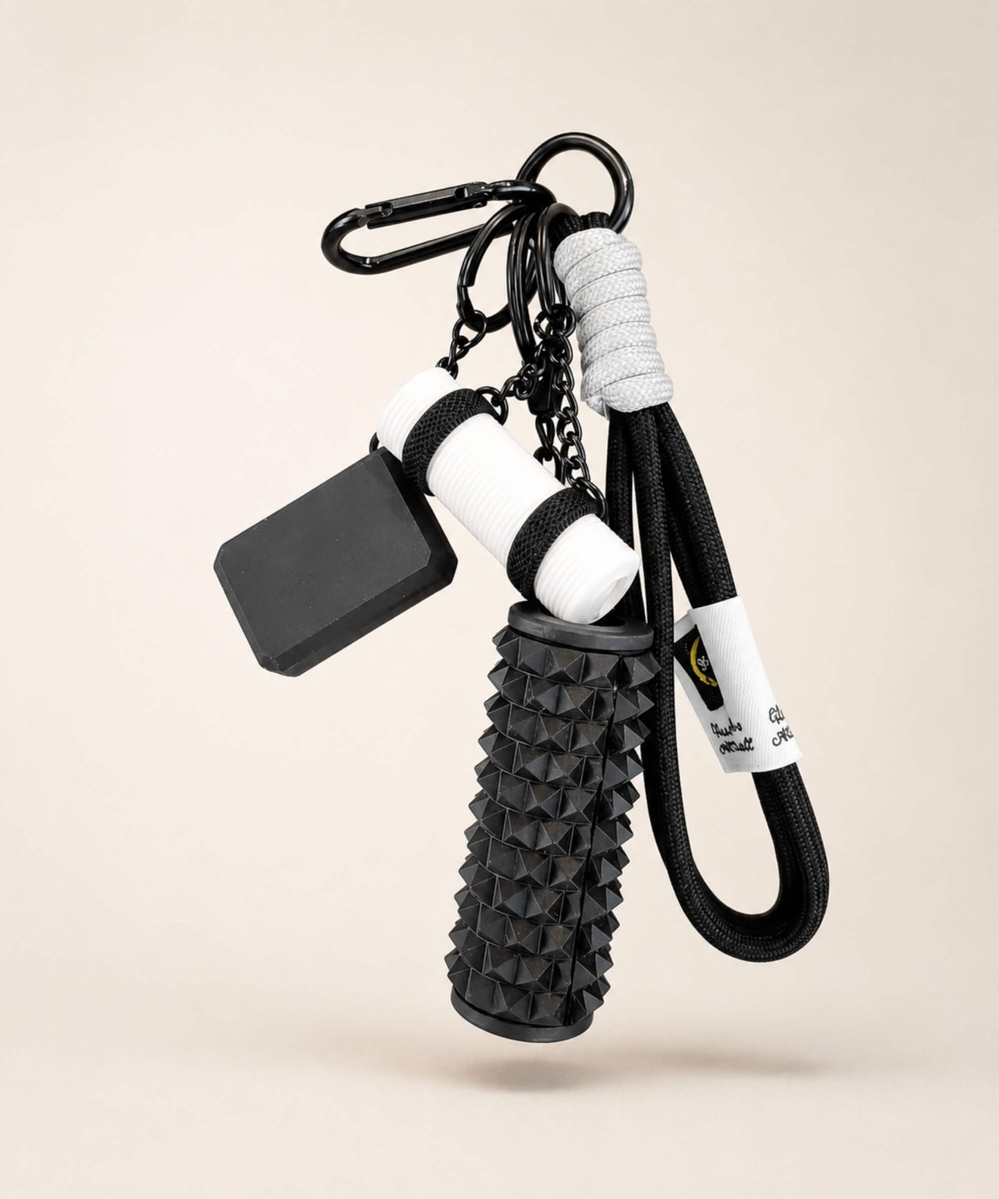 Black yoga rope keychain with black foam roller charm and white yoga mat charm on a neutral background