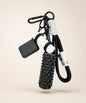Black yoga rope keychain with black foam roller charm and white yoga mat charm on a neutral background