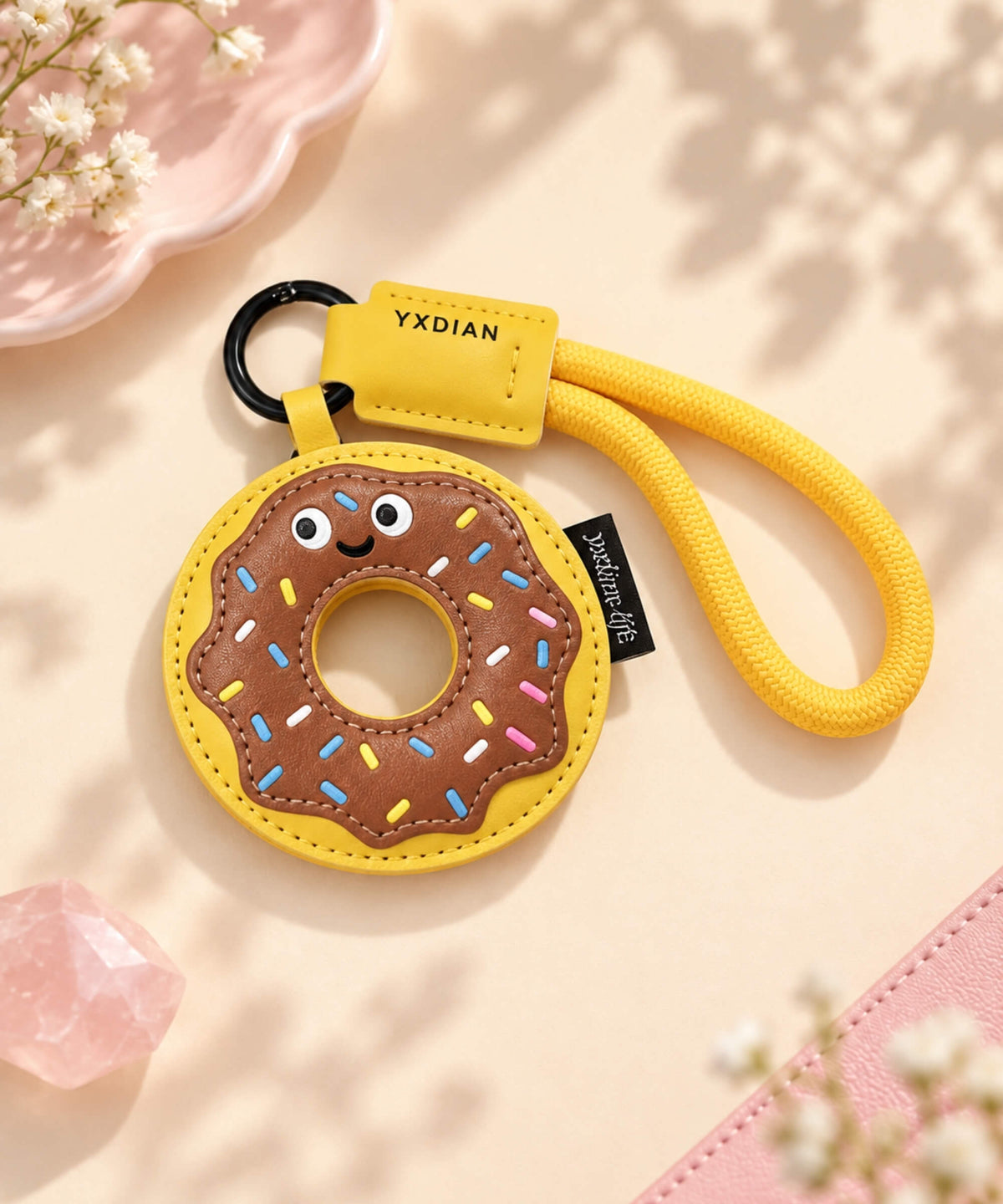 Chocolate Donut PU leather bag charm keychain with yellow rope loop on a soft neutral background