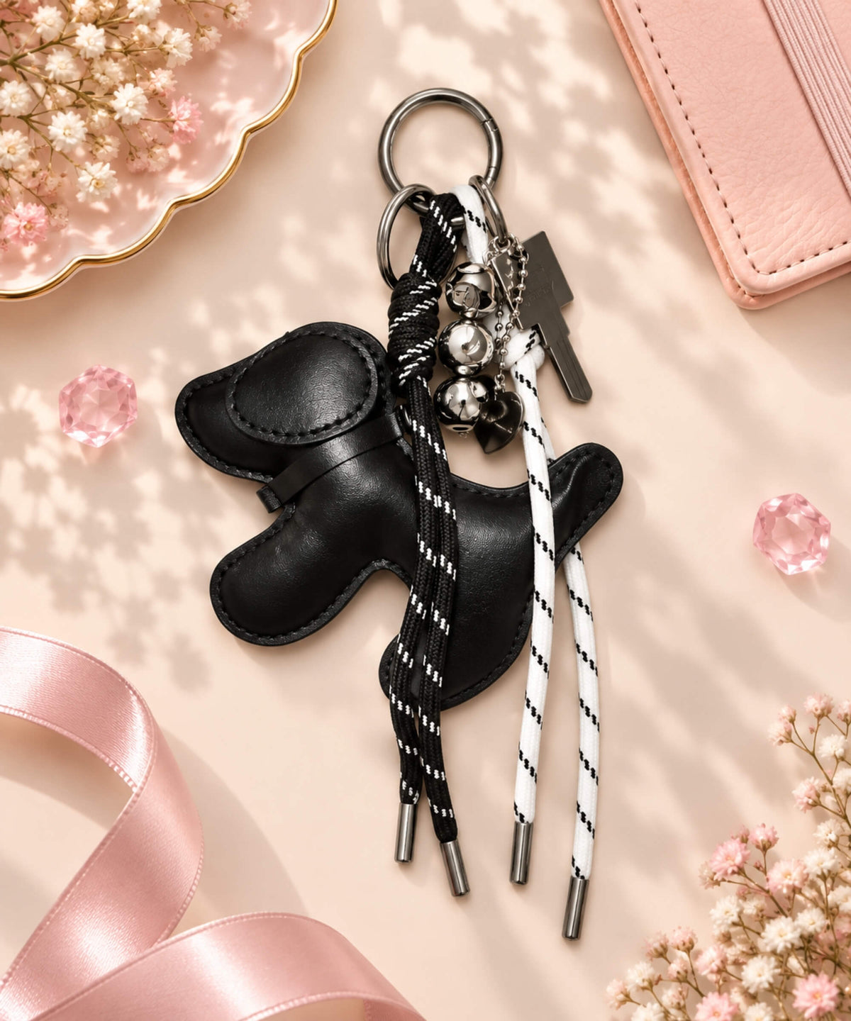 Black dog PU leather bag charm keychain styled on a soft pink background