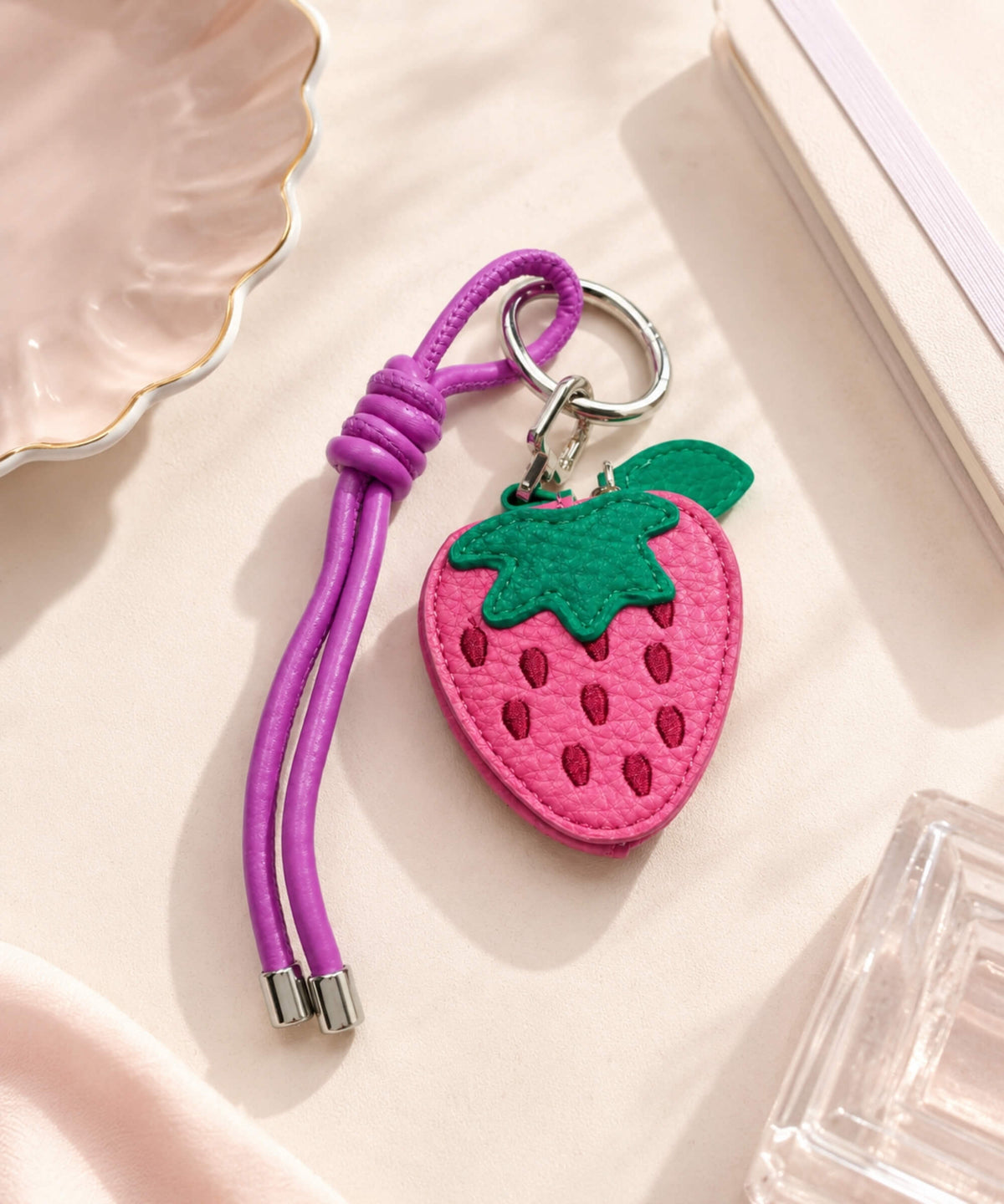 Strawberry fruit coin purse keychain with pink PU leather-style finish, green leaf detail and purple strap