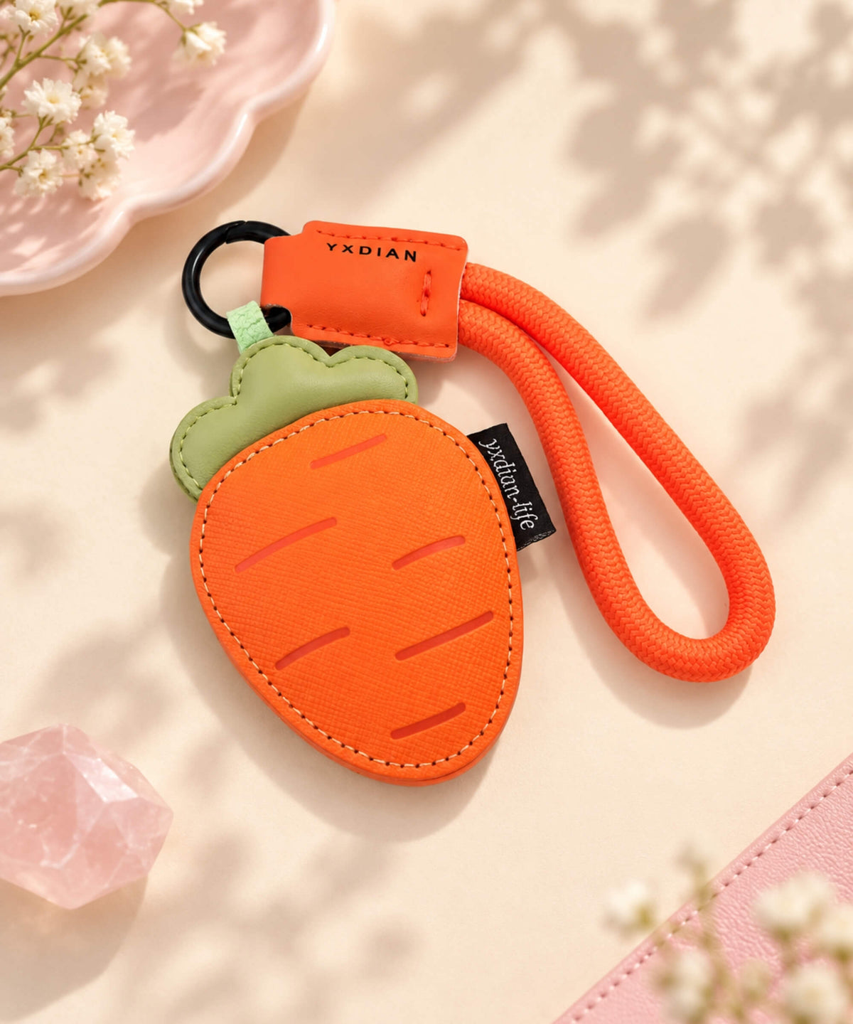 Orange carrot PU leather bag charm keychain styled on a warm neutral background