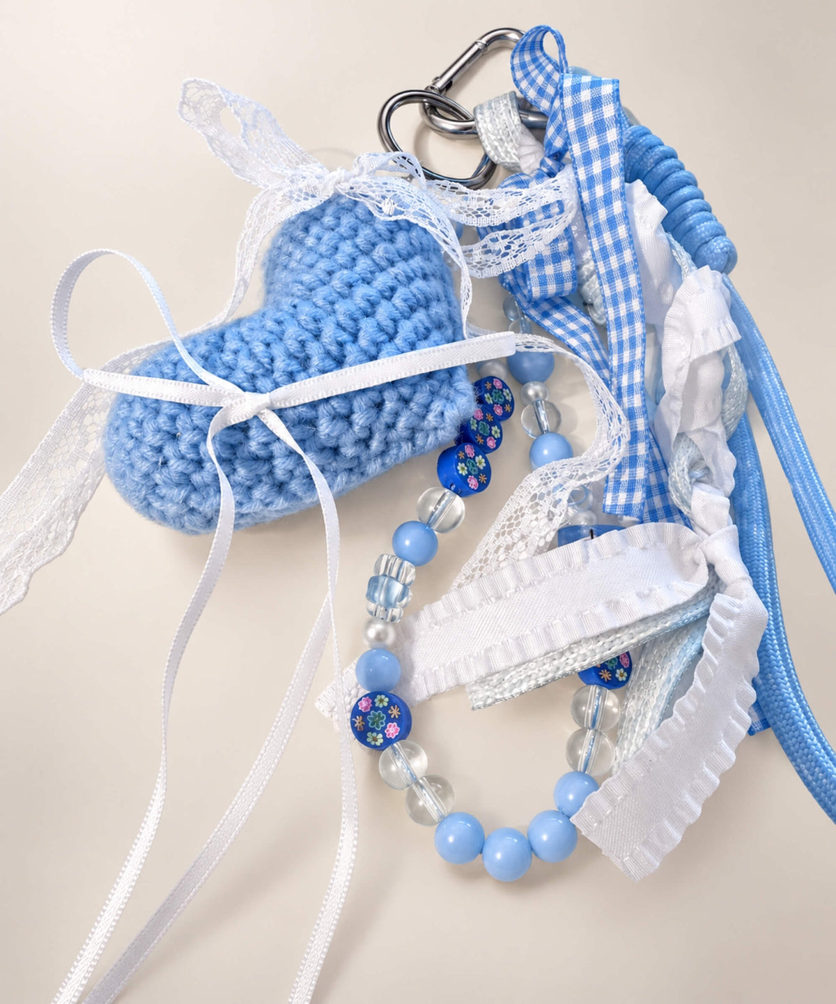 Close-up of blue heart crochet keychain with ribbons and beaded details