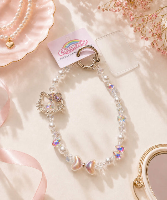 Silver Hello Kitty bow beaded phone charm with pearl-look and crystal-style beads in a soft pink lifestyle setting