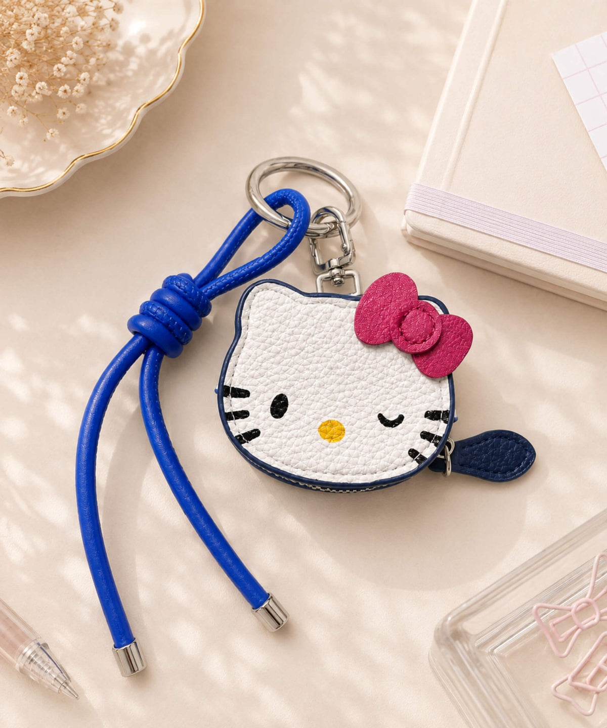 Hello Kitty coin purse keychain with white cat face design, pink bow, blue strap and PU leather-style finish