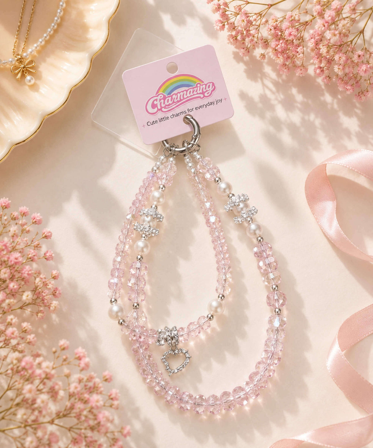 Hello Kitty pearl heart beaded phone charm styled in a soft pastel lifestyle setting with pink crystal-style beads and pearl accents