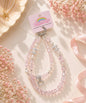 Hello Kitty pearl heart beaded phone charm styled in a soft pastel lifestyle setting with pink crystal-style beads and pearl accents