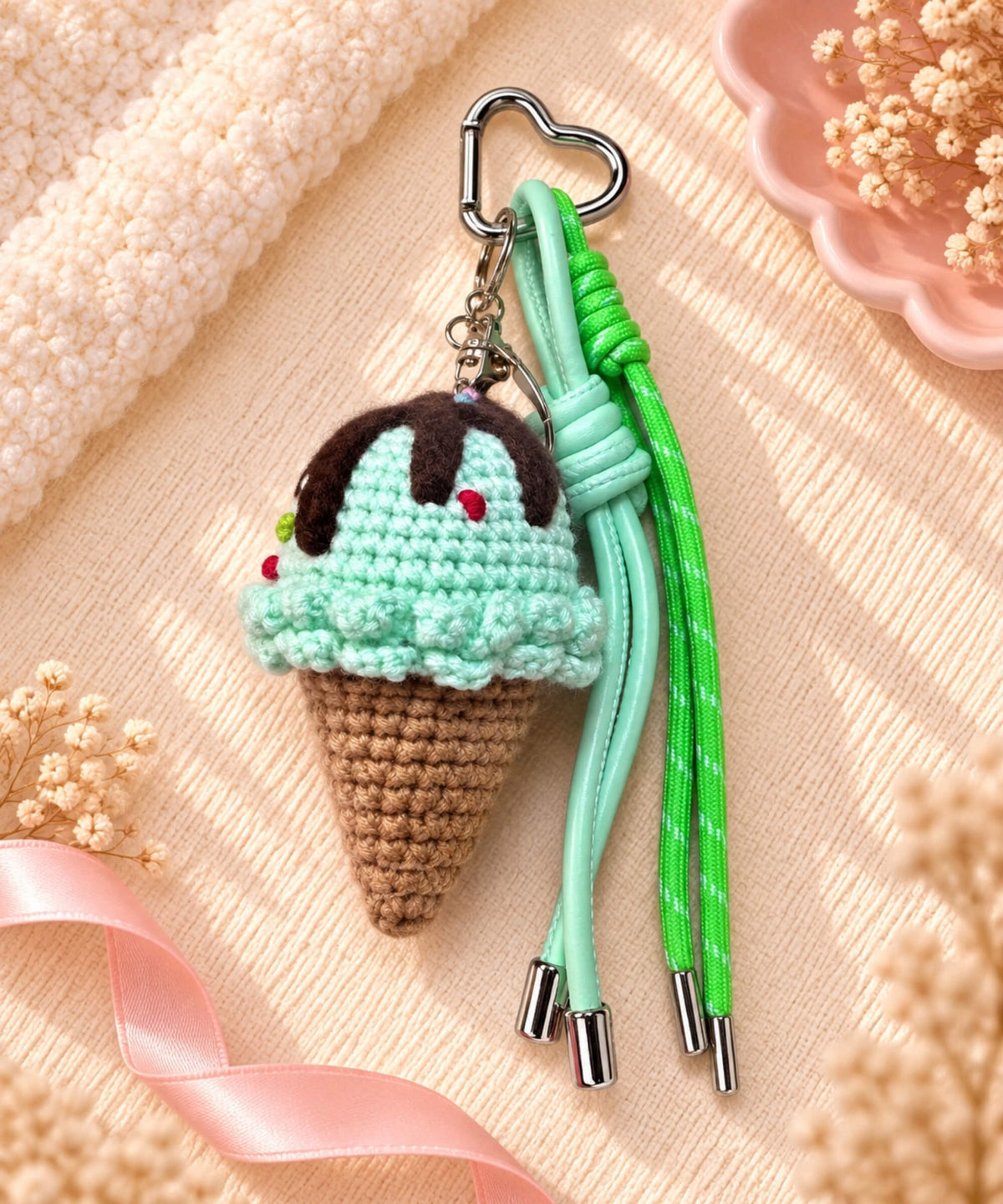 Mint scoop ice cream crochet keychain styled on a soft cream fabric background