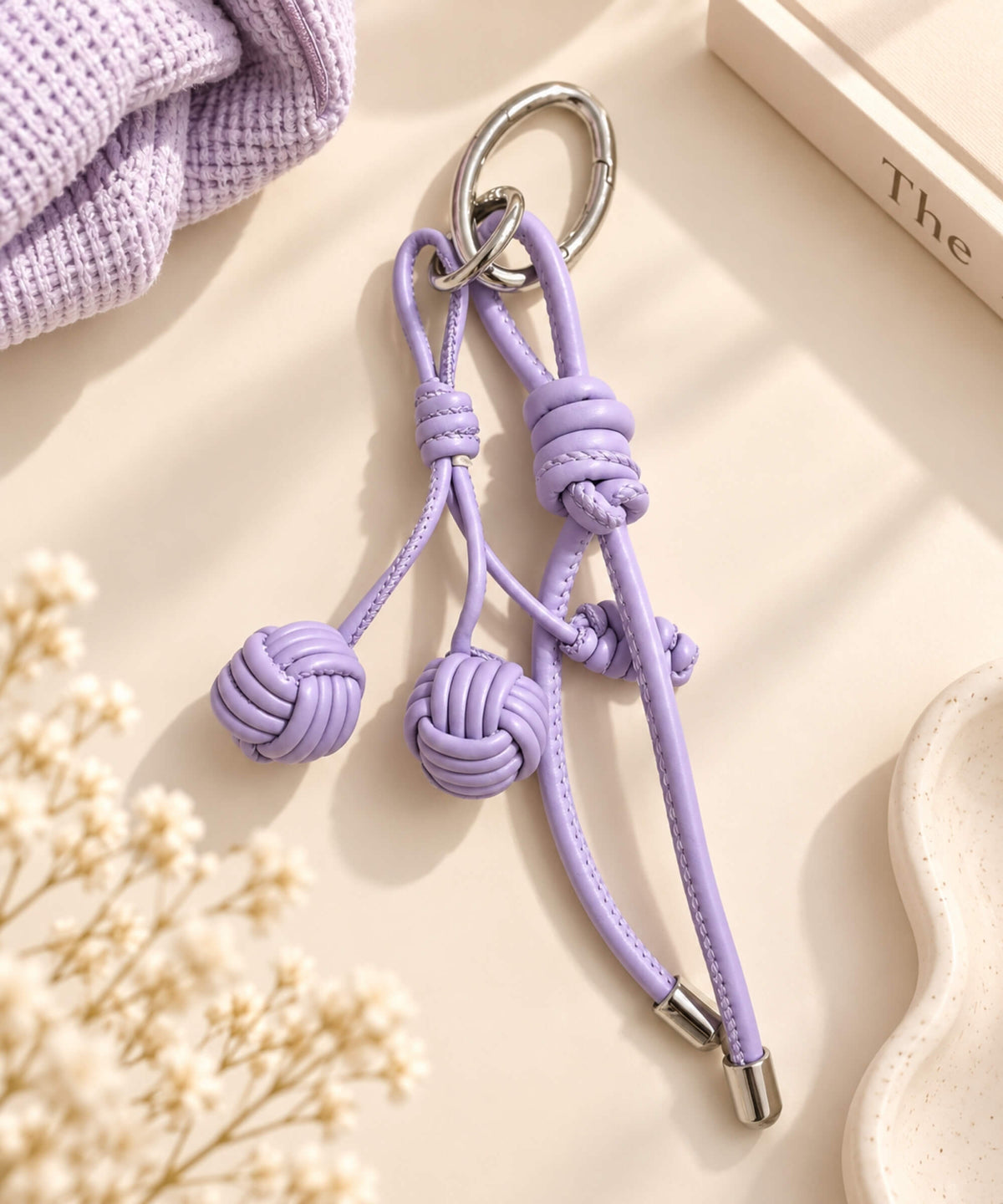 Purple knotted ball PU leather bag charm keychain styled on a neutral background
