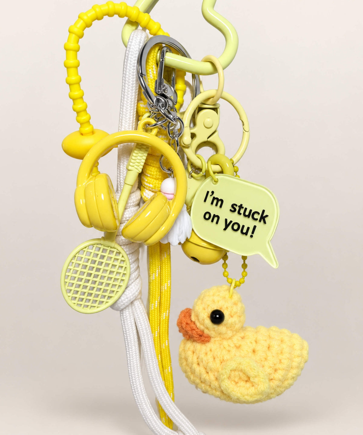 Close up of Stuck on You Duck crochet keychain with headphones racket and yellow message charm