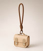 Beige mini PU leather earphone pouch keychain with brown wrist strap on a neutral background