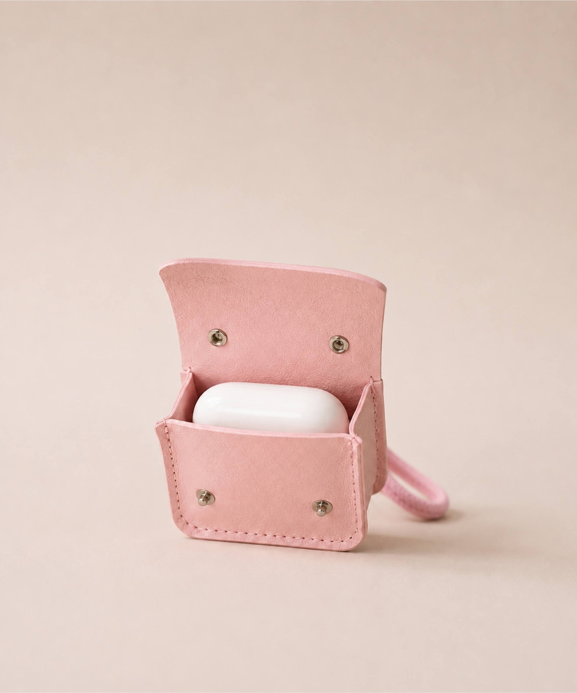 Open pink mini PU leather earphone pouch keychain showing a white earbud case inside