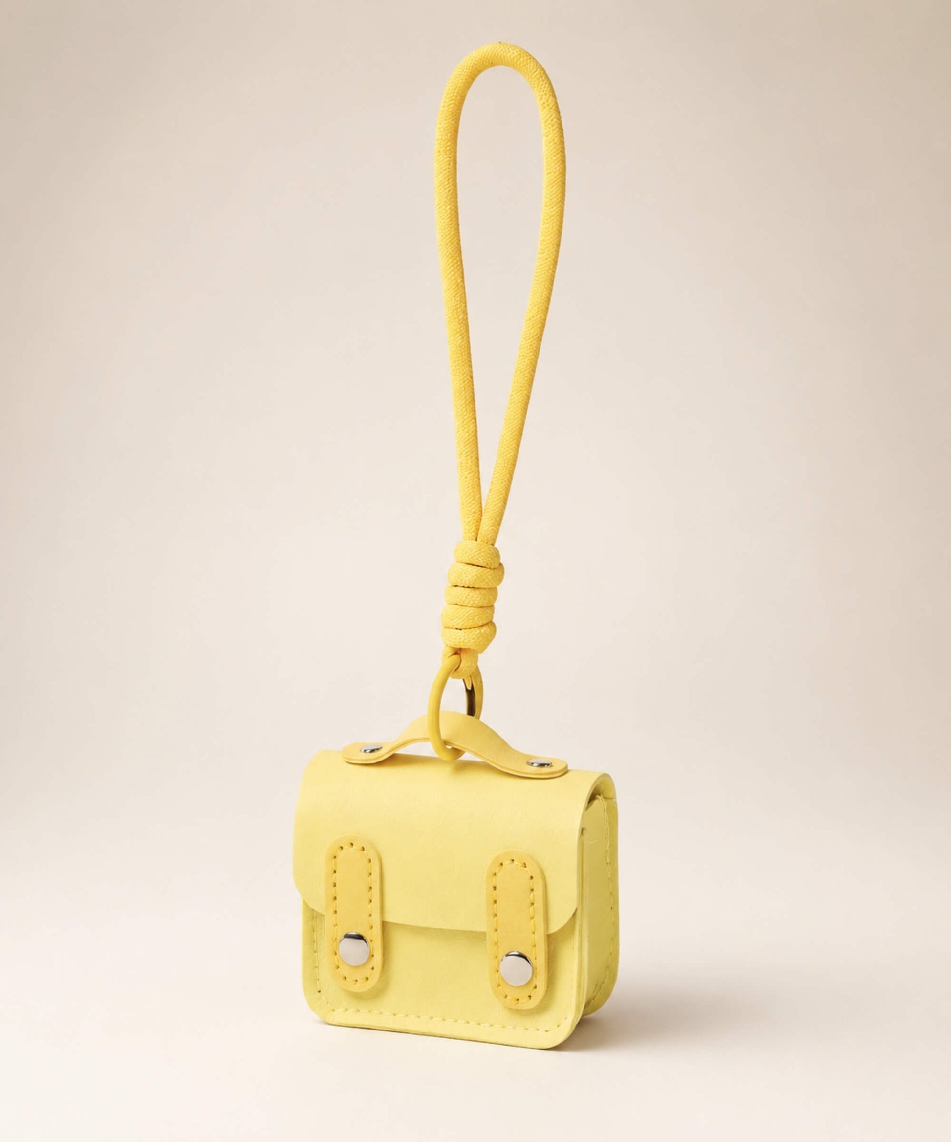 Yellow mini PU leather earphone pouch keychain with wrist strap on a neutral background