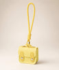 Yellow mini PU leather earphone pouch keychain with wrist strap on a neutral background