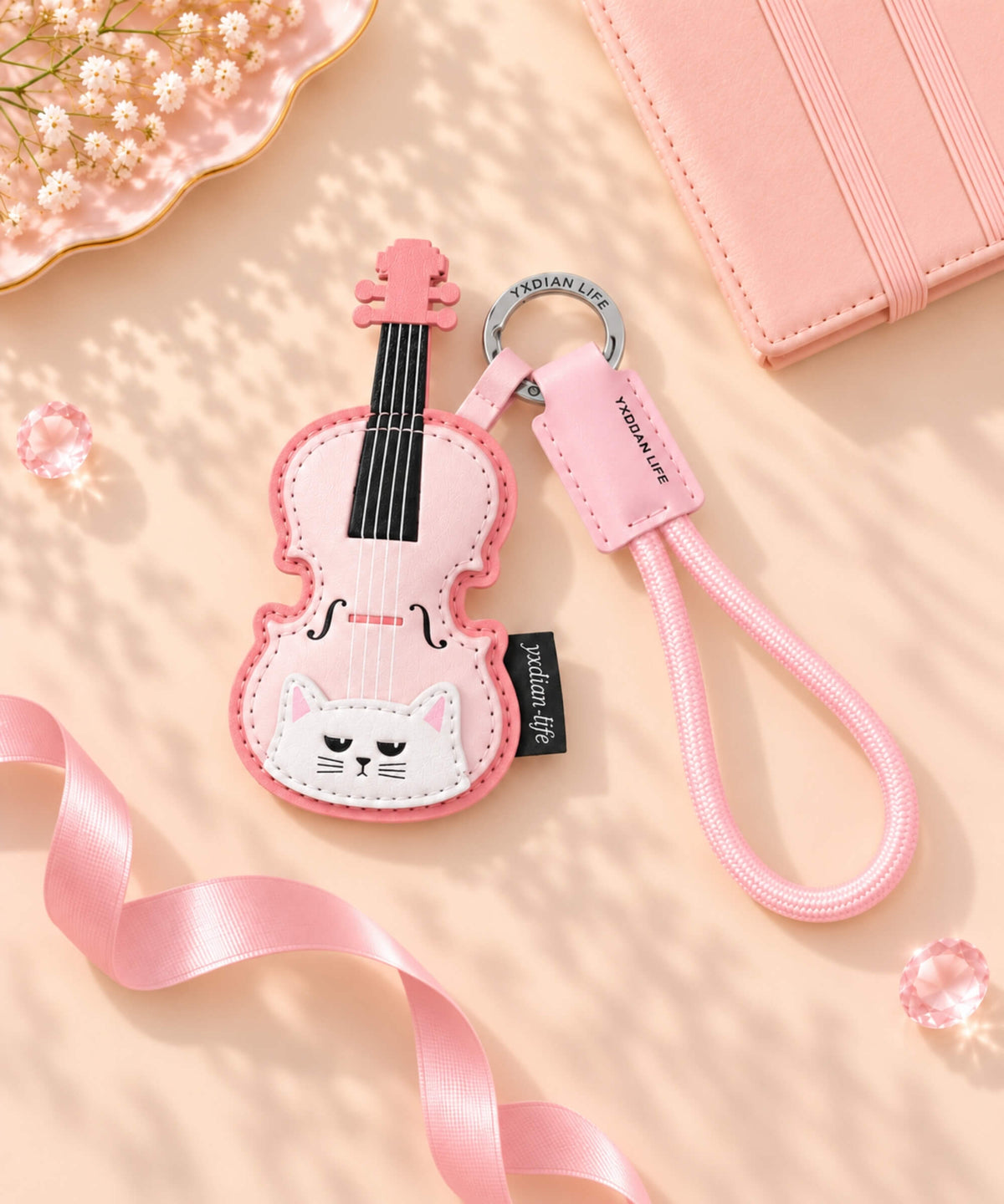 Pink violin cat PU leather bag charm keychain styled on a soft pink background