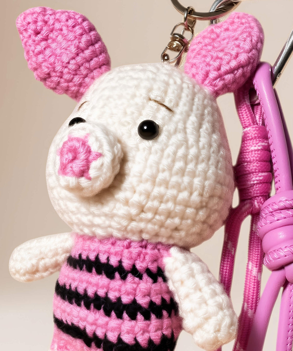 Close-up detail of Piglet style crochet keychain with pink and black striped body