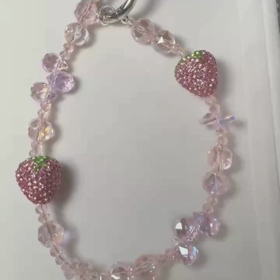 Video of a strawberry beaded phone charm featuring crystal-style beads and sparkling strawberry details by CHARMAZIN