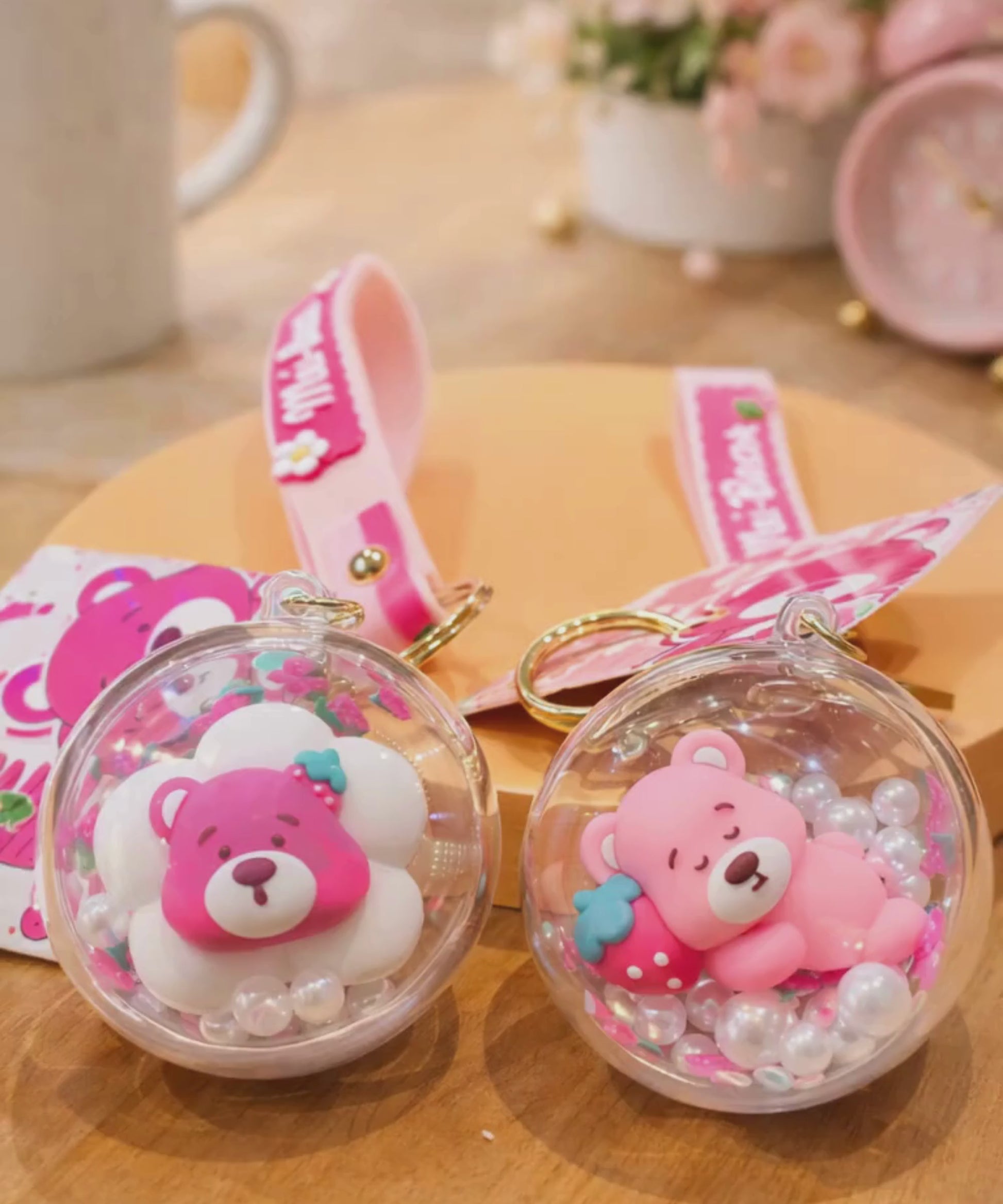 Strawberry bear shaker keychain with floating beads displayed in lifestyle setting