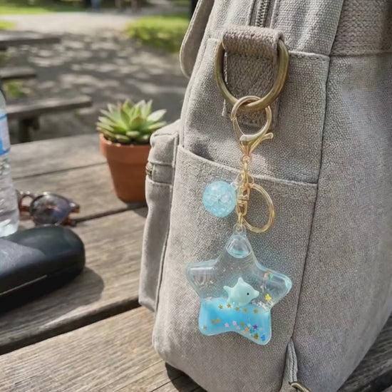Star liquid glitter keychain blue bag charm hanging on backpack outdoor lifestyle scene