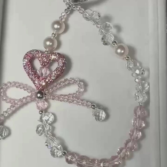 Video of pink heart bow beaded phone charm with crystal-style beads and sparkling heart detail