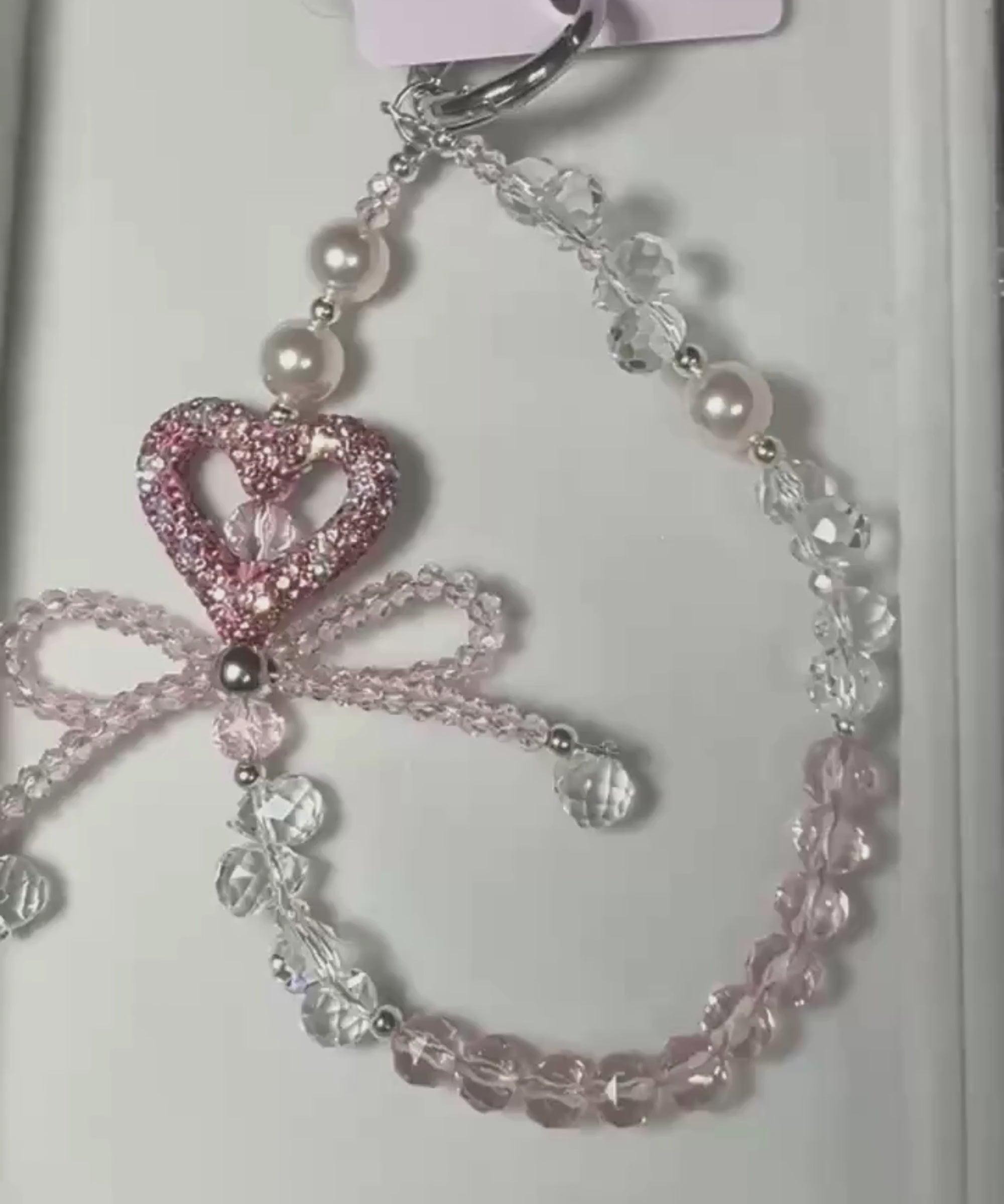 Video of pink heart bow beaded phone charm with crystal-style beads and sparkling heart detail