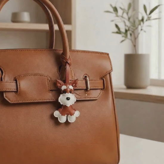 Brown Cute Schnauzer PU leather bag charm attached to a tan handbag being picked up in a lifestyle video.
