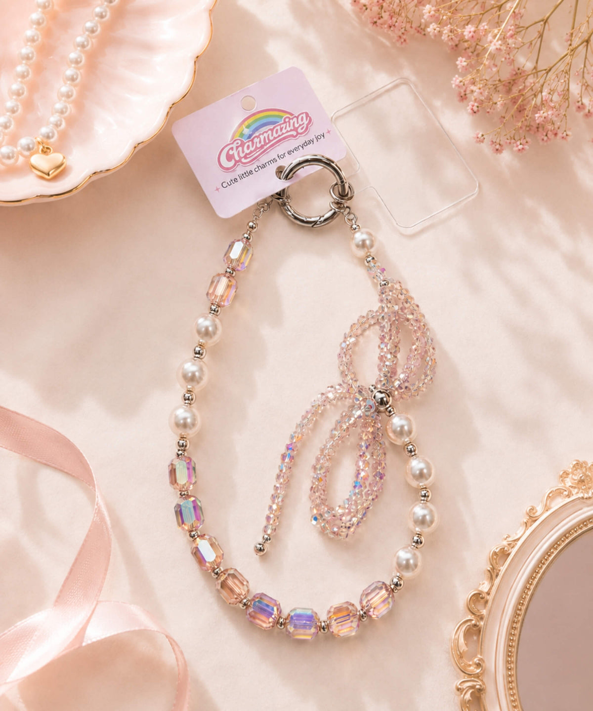 Pink ribbon bow beaded phone charm styled in a soft pastel lifestyle setting