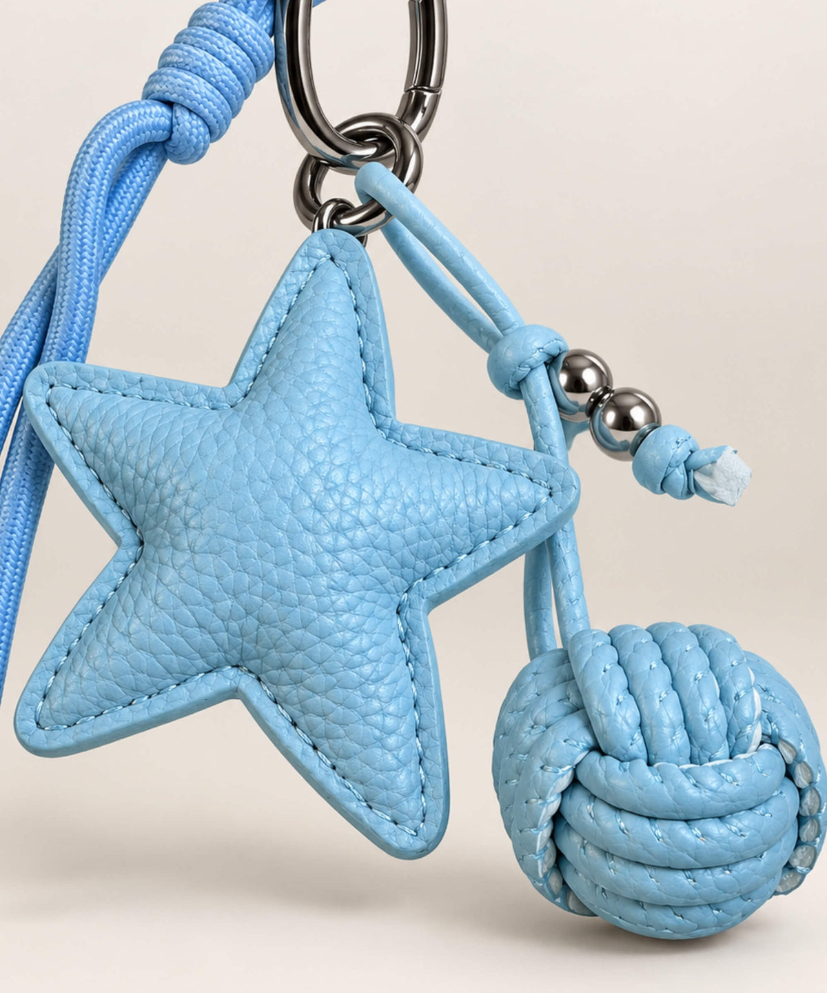 Close-up of Blue star PU leather bag charm keychain showing stitched star and woven knot detail