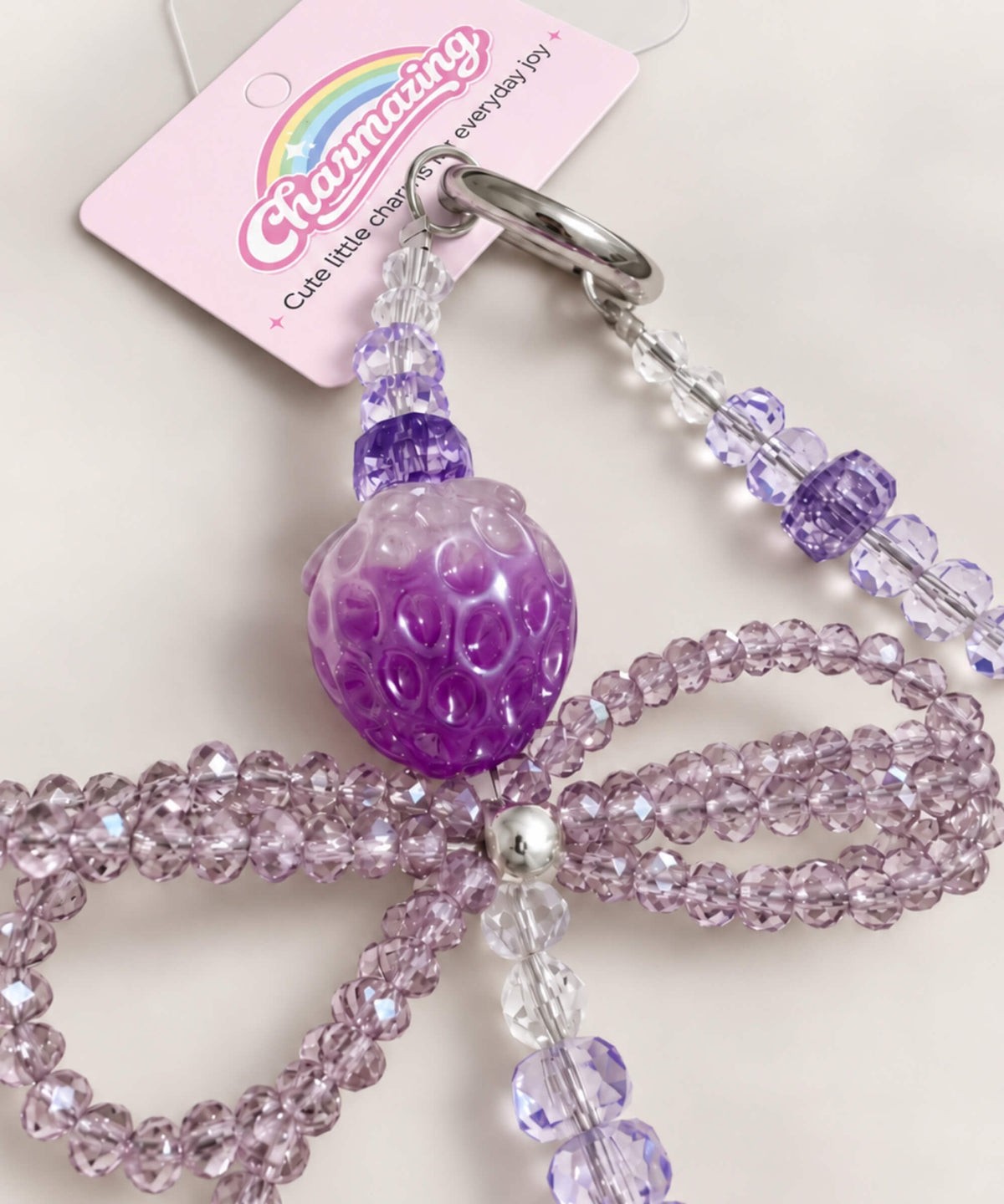 Close-up detail of the purple strawberry bow beaded phone charm with glossy strawberry bead and sparkly bow design