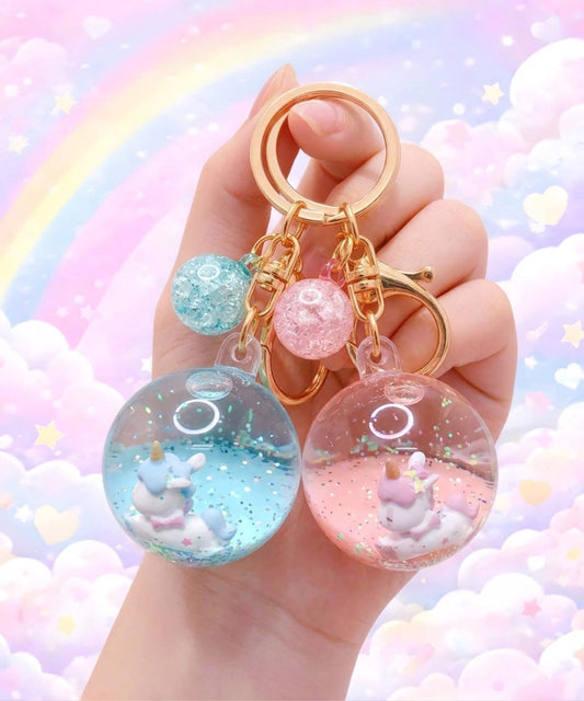 Unicorn liquid glitter keychains in blue and pink colours held in hand, cute floating acrylic bag charms with sparkles and pastel background