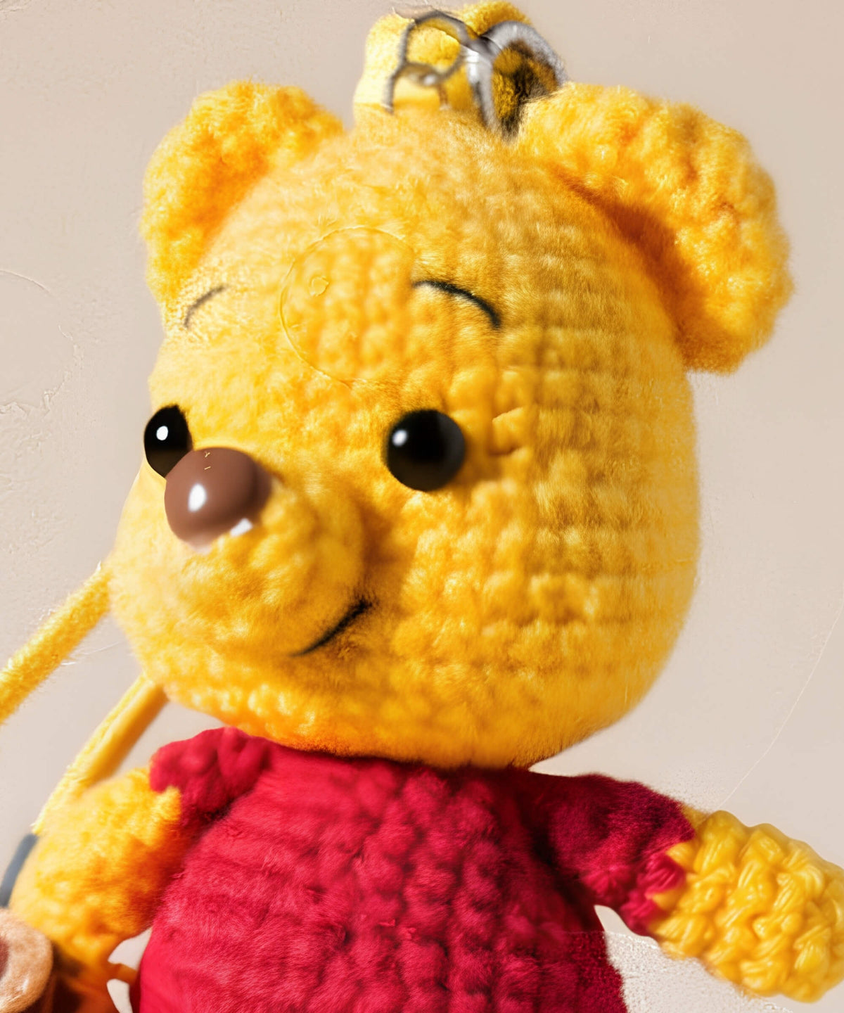 Close-up detail of Winnie the Pooh style crochet keychain with yellow crochet finish